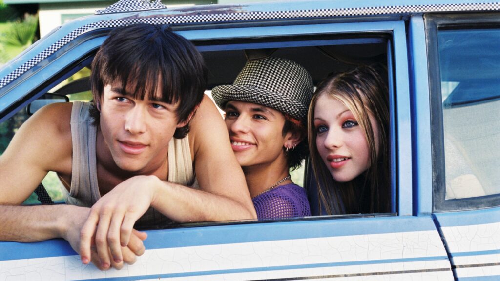 Joseph Gordon-Levitt wears a white tank top and hangs out the window of a cab. Jeffrey Licon and Michelle Trachtenberg sit behind him.